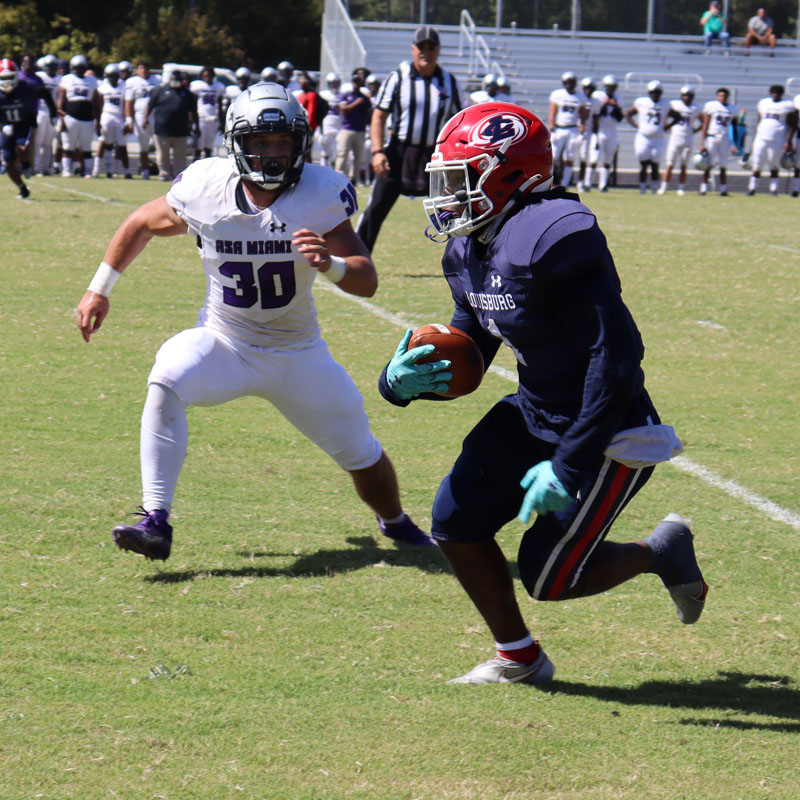 Football player carrying the ball in game action.