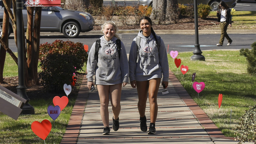 Two female students walking across campus