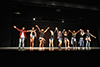 Young adults stand on light stage giving their final ovation after a dance performance