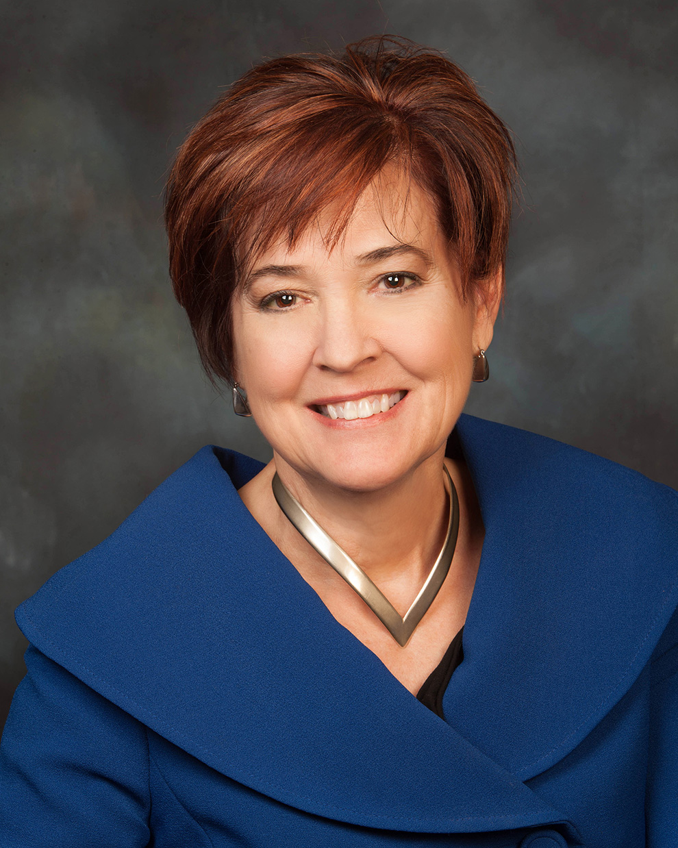 A portrait of Bonnie Suderman, a smiling woman with short brown hair, wearing a blue jacket.