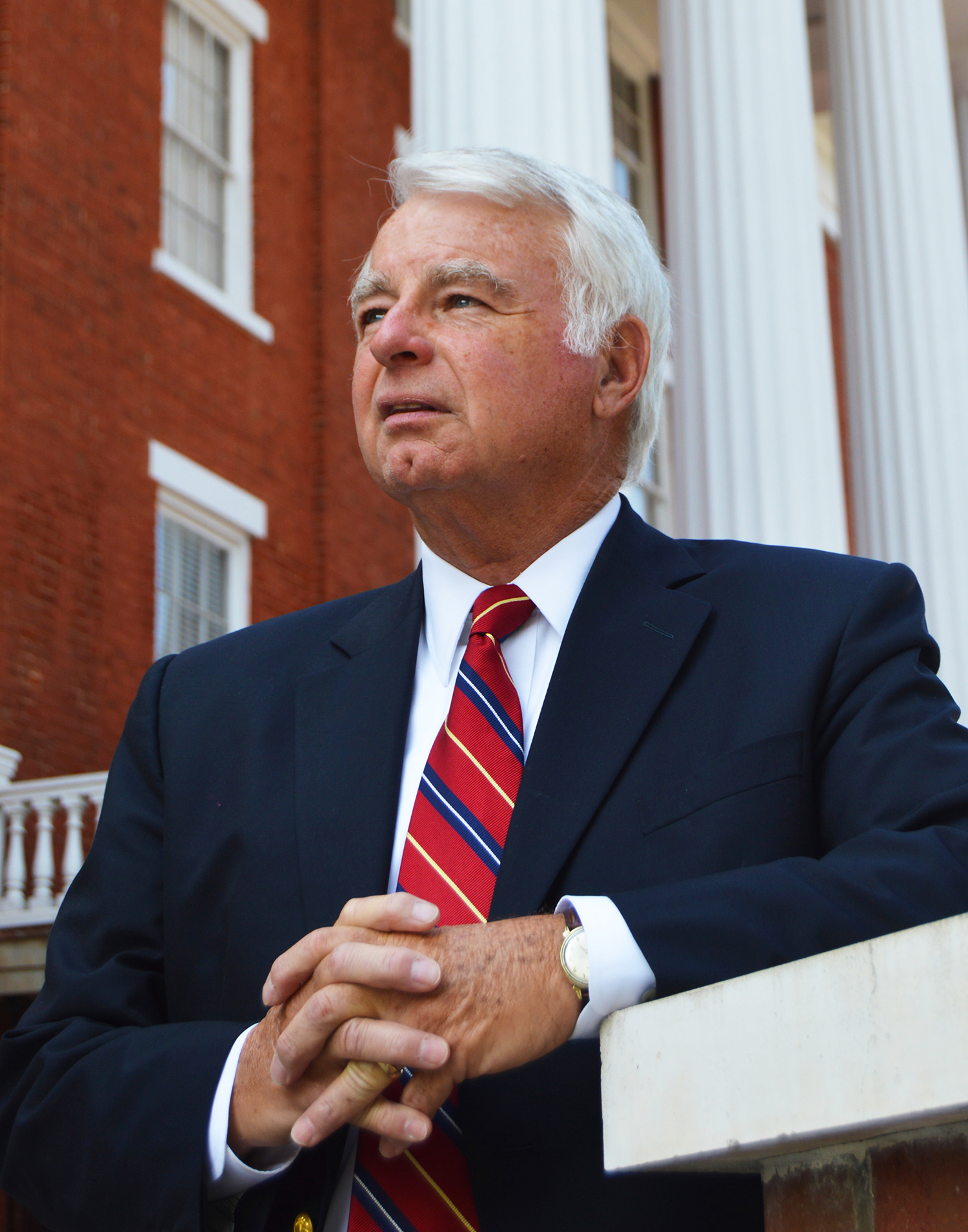 man wearing suit standing against brick building